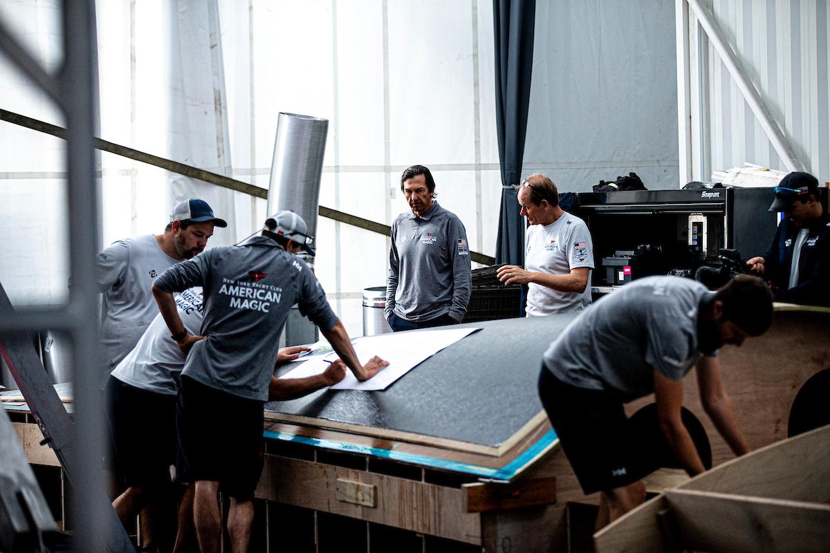 Design team members and boatbuilders prepare the replacement hull panel for installation. © Sailing Energy / American Magic