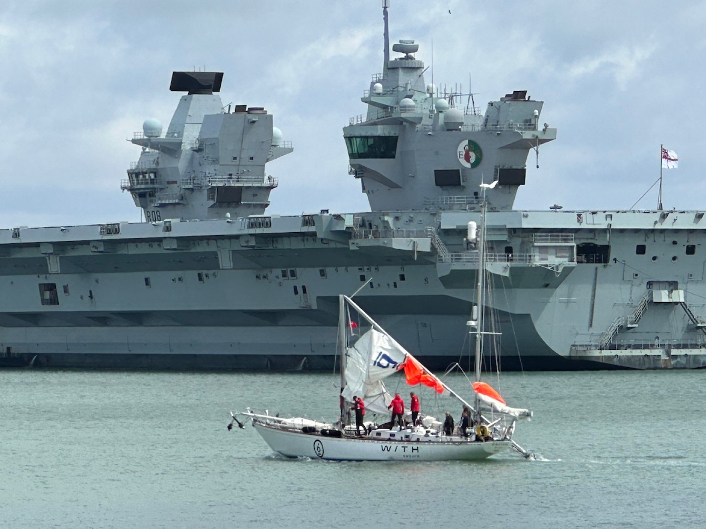 Galiana WithSecure FI (06) passing HMS Queen Elizabeth after dismasting in the Fastnet Race. Down but not out. Photo Credit: Rob Havill / OGR2023